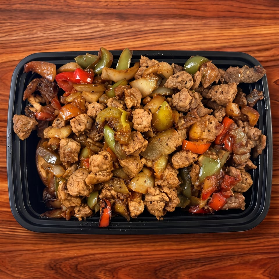 Stir-fried beef and chicken with bell peppers and onions in a black takeout container.